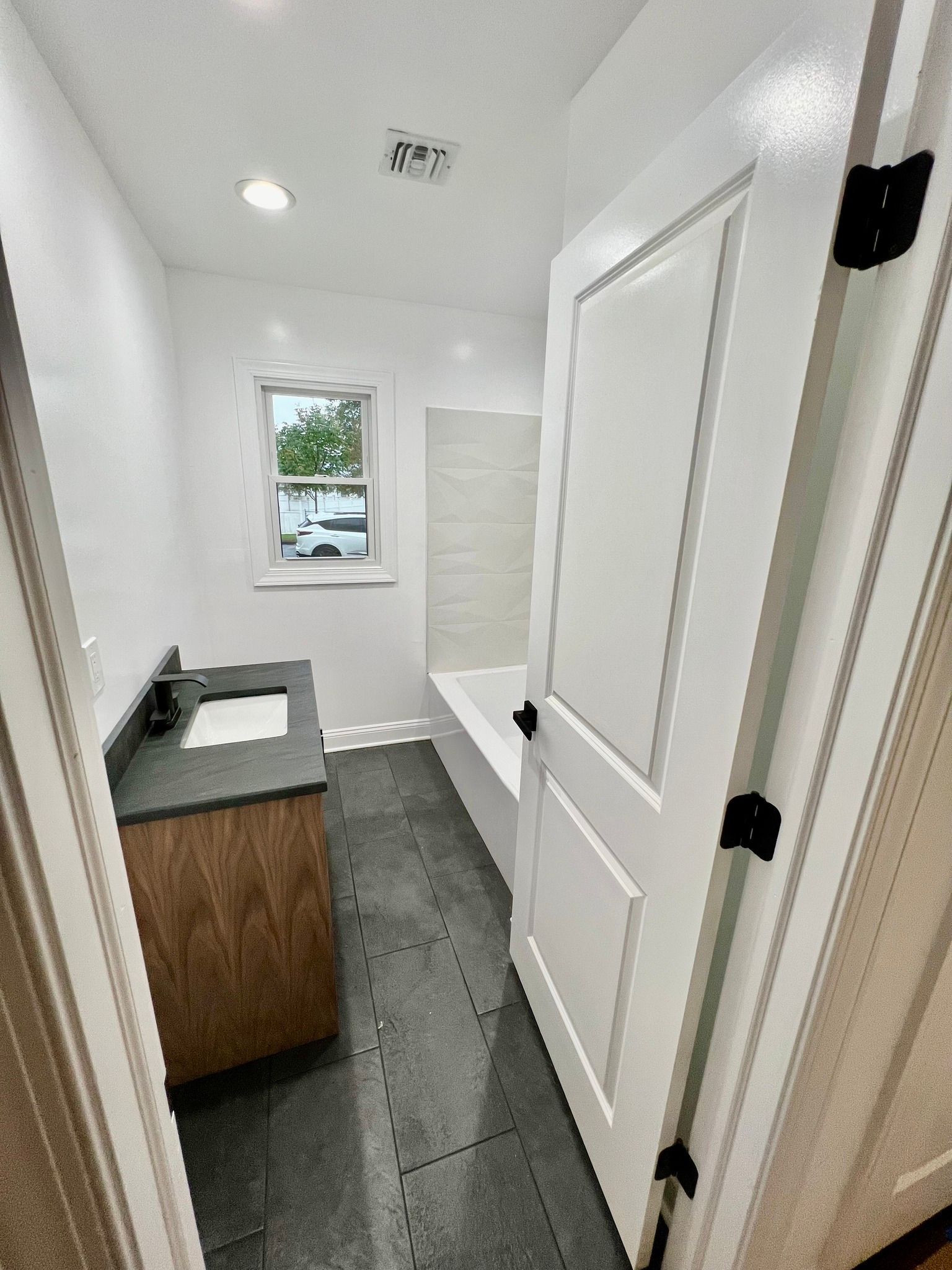 A bathroom with a sink , tub , and window.