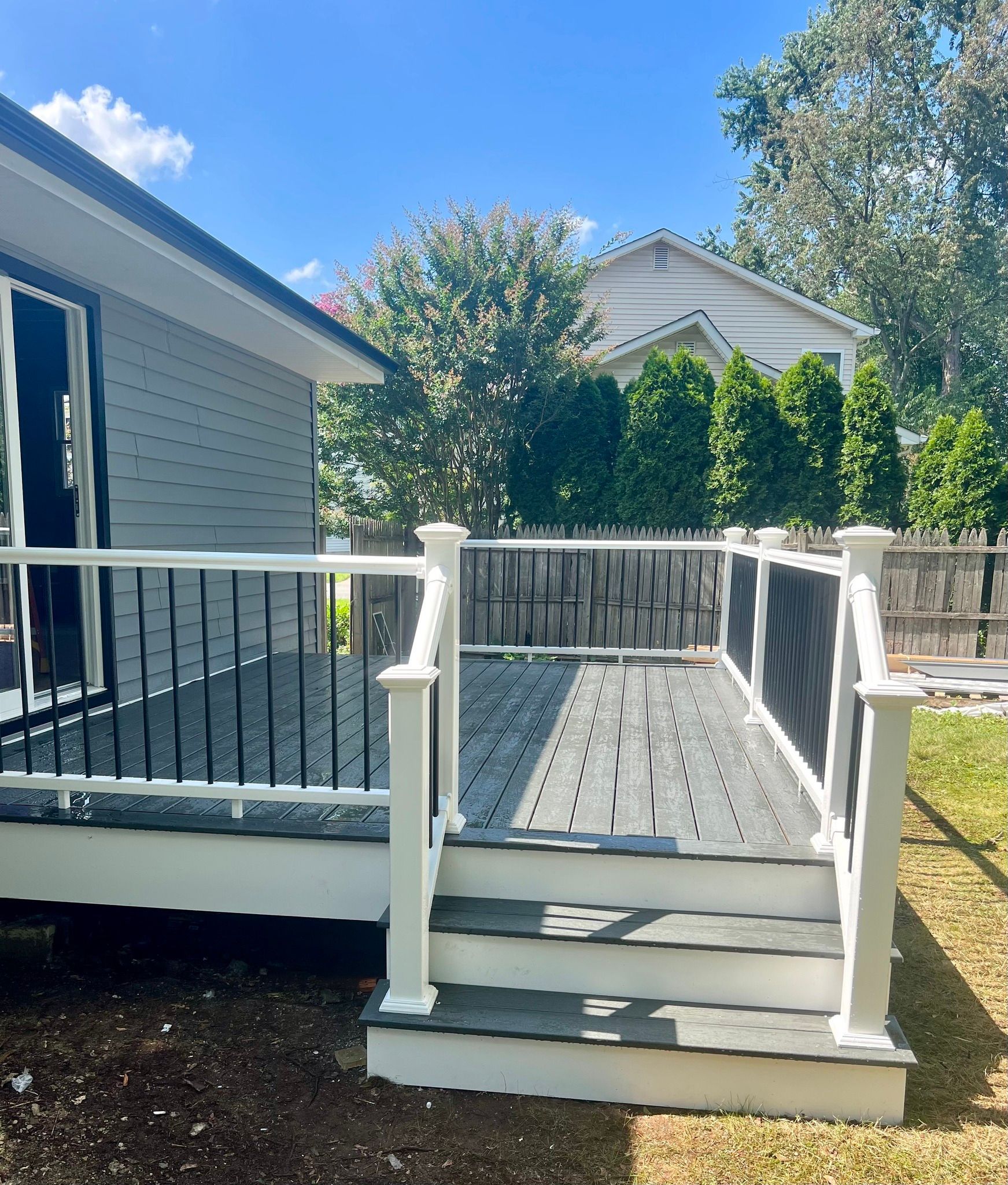 A deck with stairs leading up to it is in the backyard of a house.
