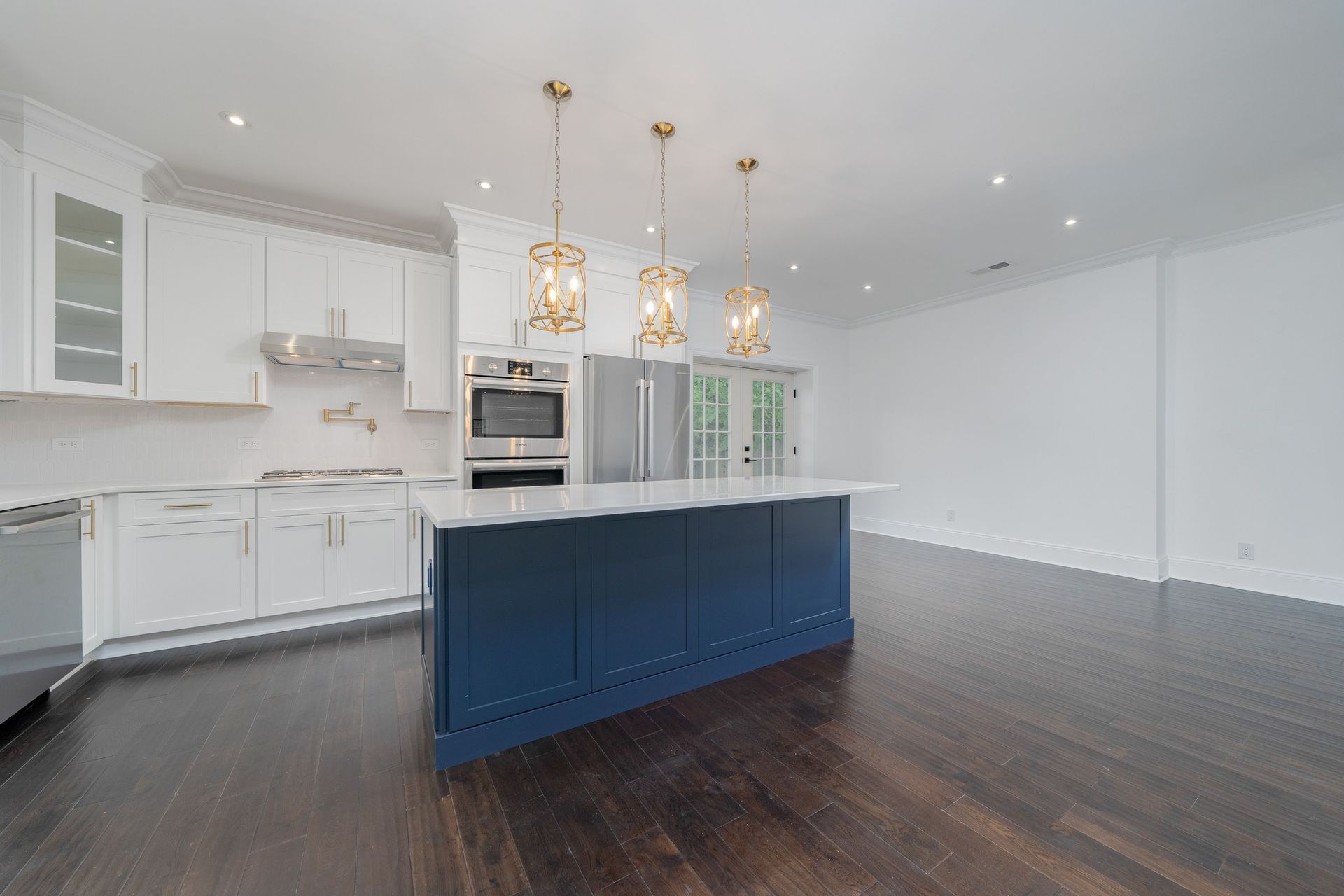 An empty kitchen with white cabinets and a blue island.