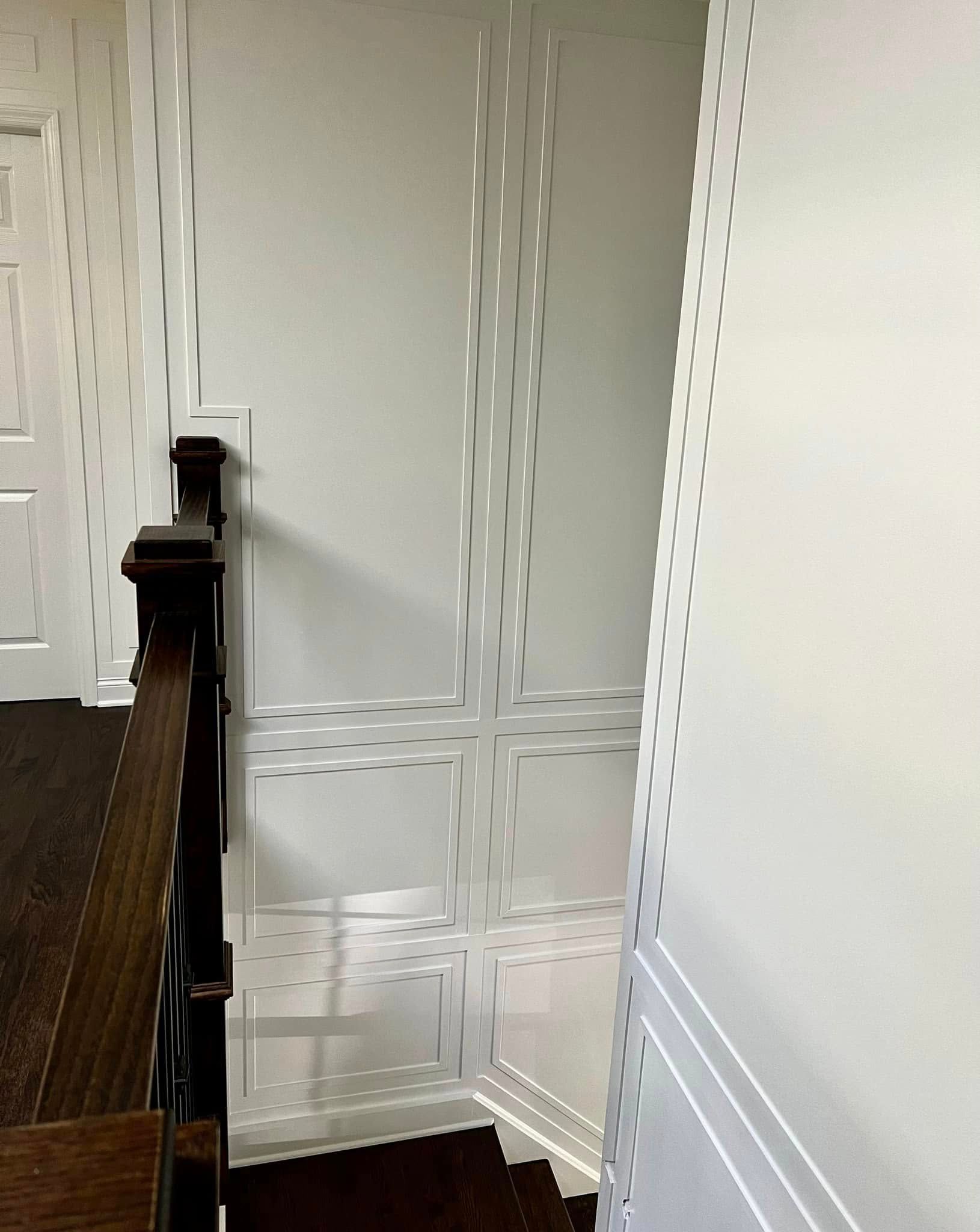 A staircase with a wooden railing and a white wall.