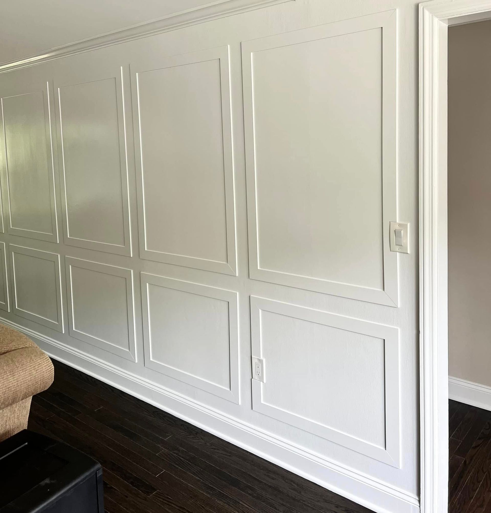 A living room with white walls and a black ottoman