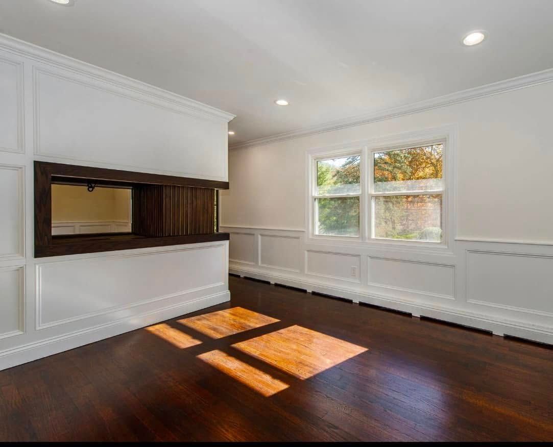 An empty living room with hardwood floors and white walls.