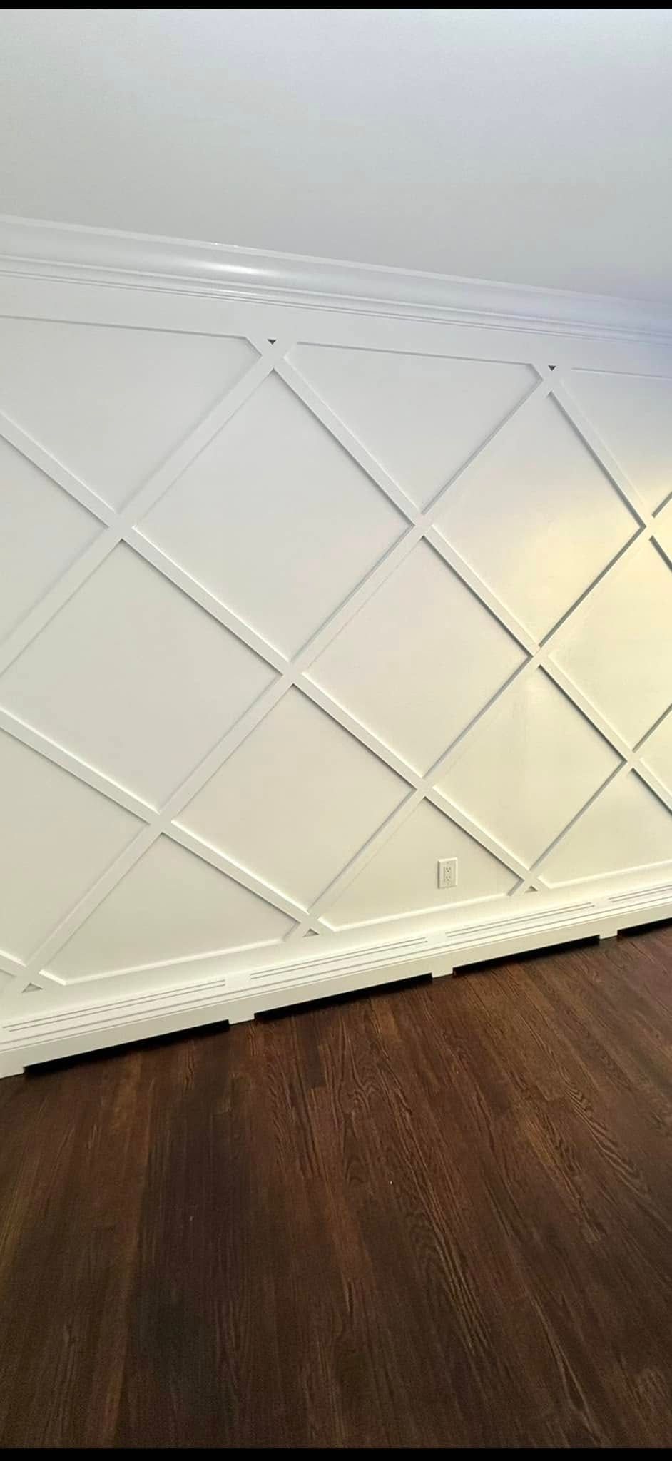 A white wall with a pattern on it is sitting on top of a wooden floor.