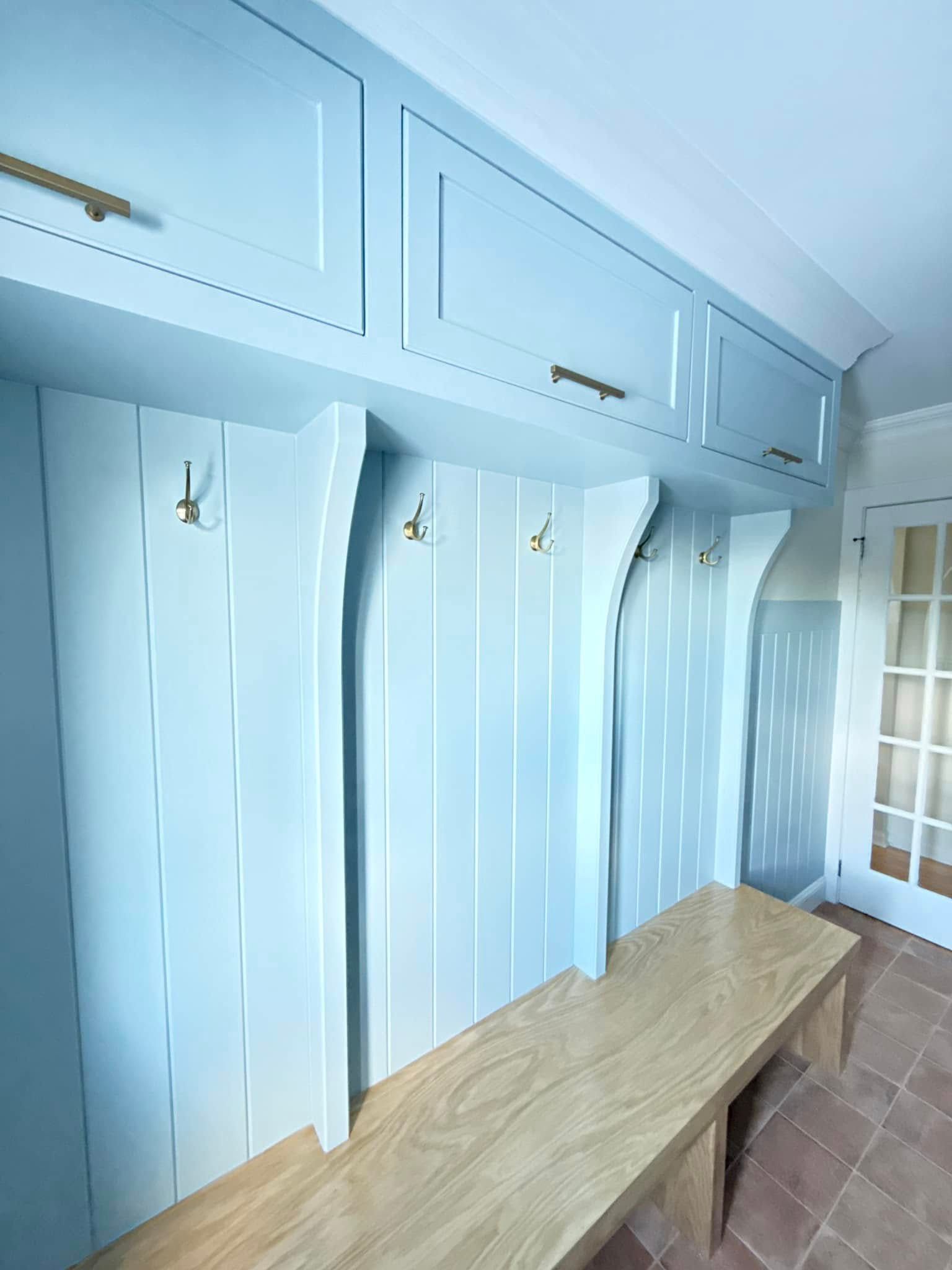 A hallway with a wooden bench and hooks on the wall.