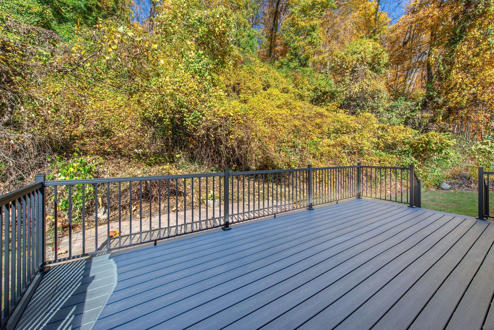 An empty deck with a railing and trees in the background.