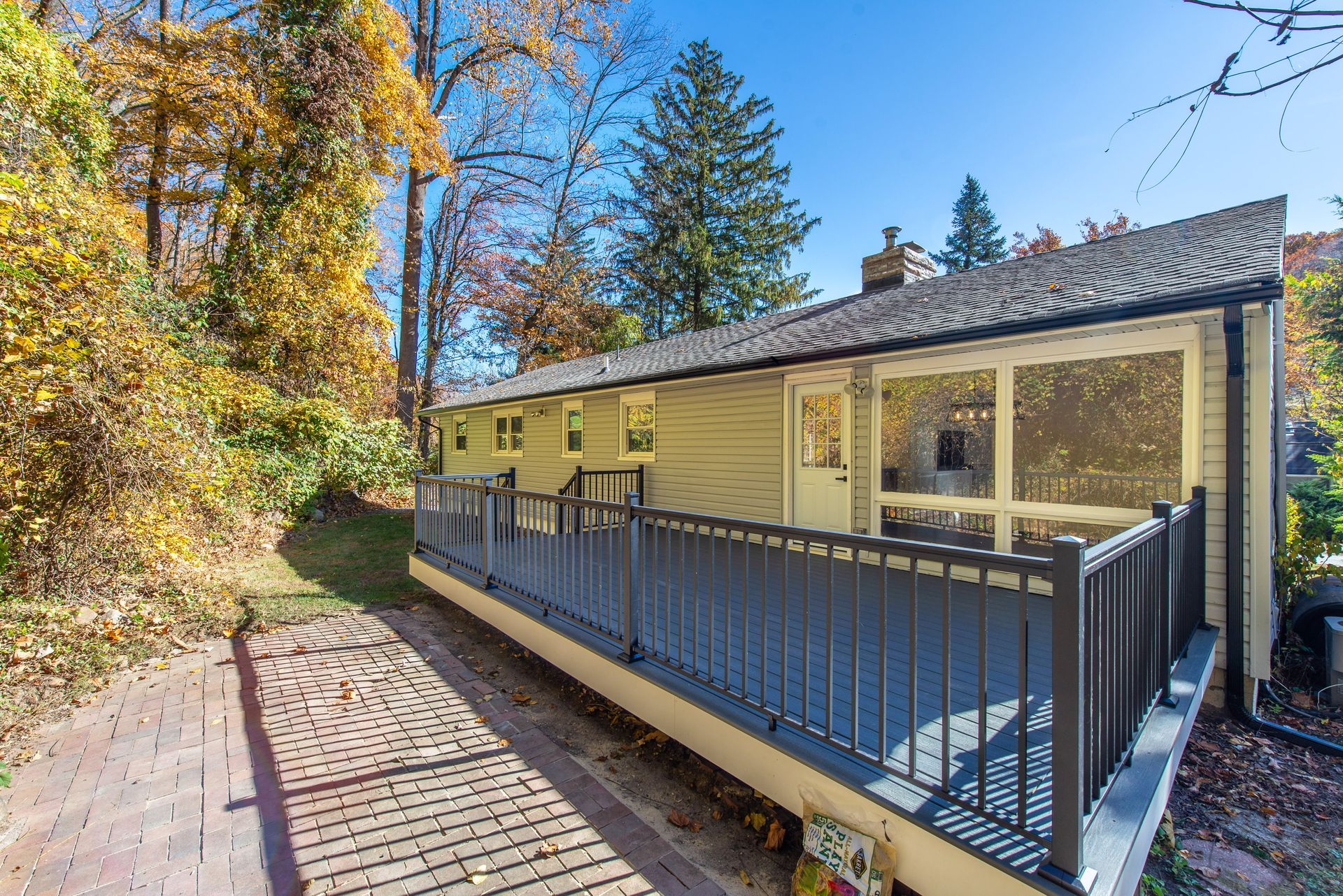 A yellow house with a large deck surrounded by trees.