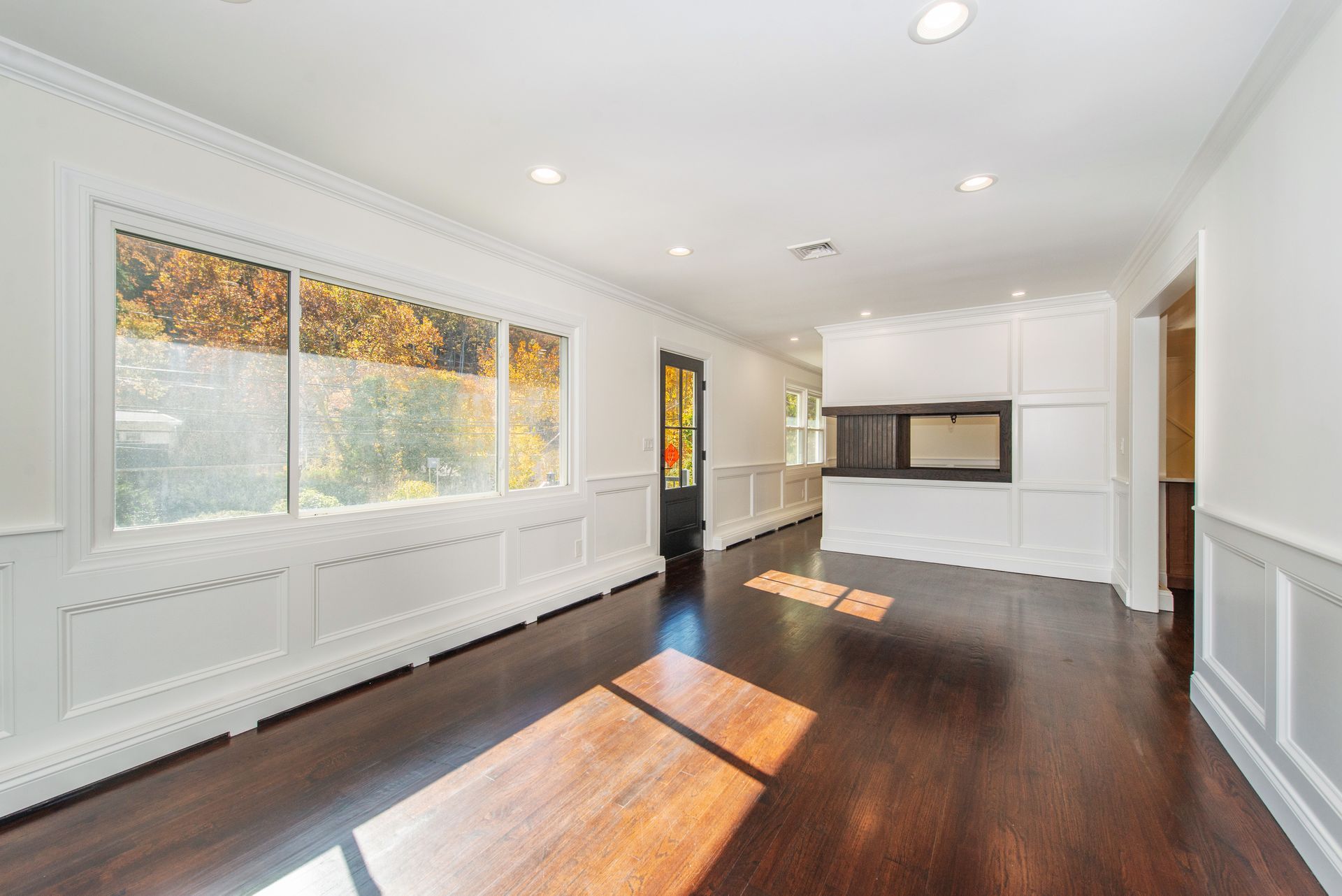 An empty living room with hardwood floors and white walls.