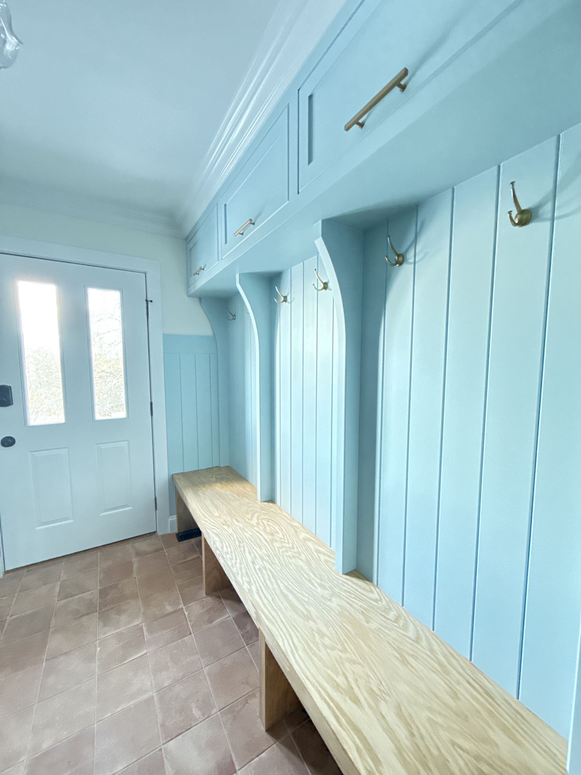 A hallway with a bench and hooks on the wall.