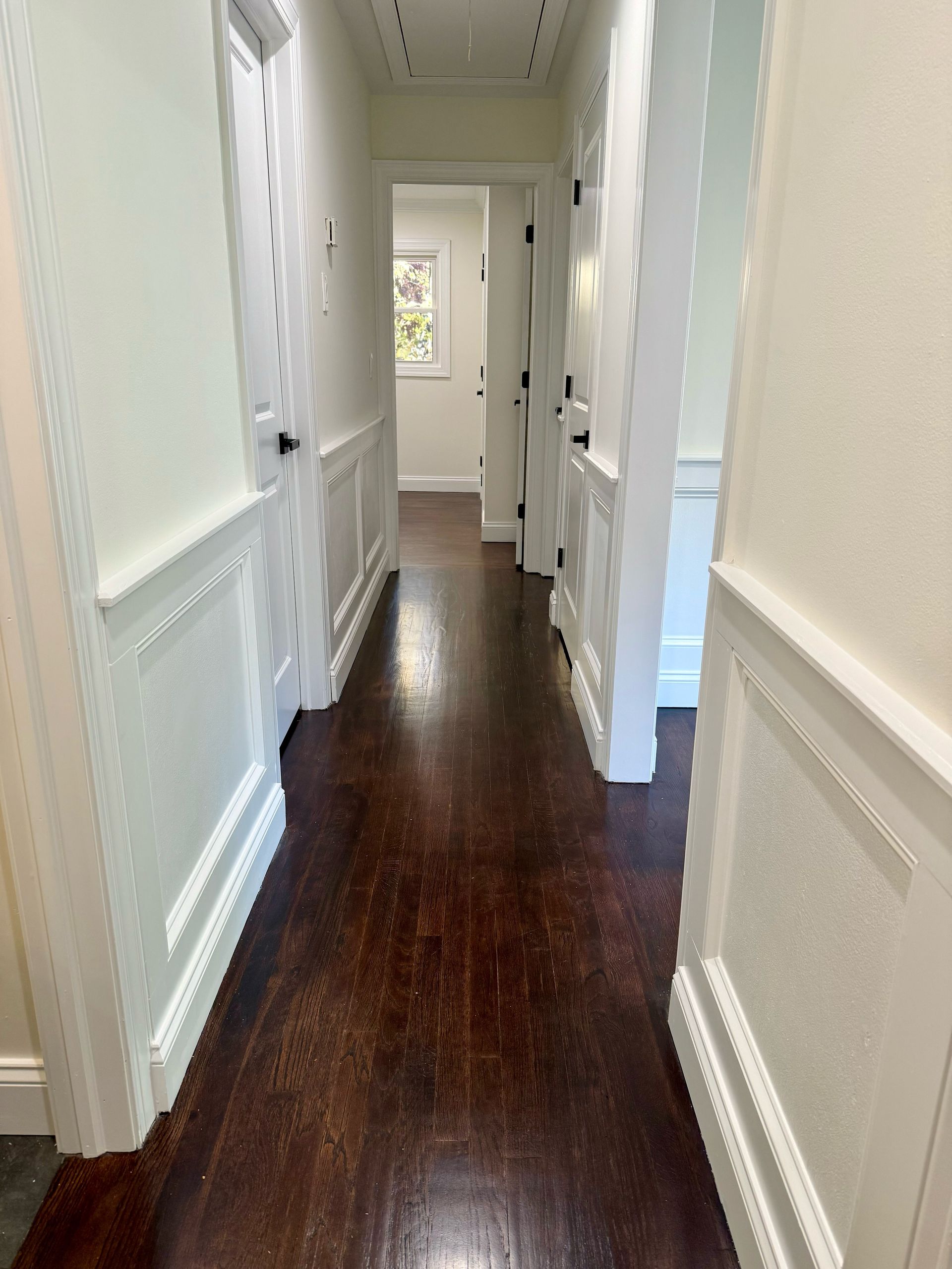 A long hallway with hardwood floors and white walls