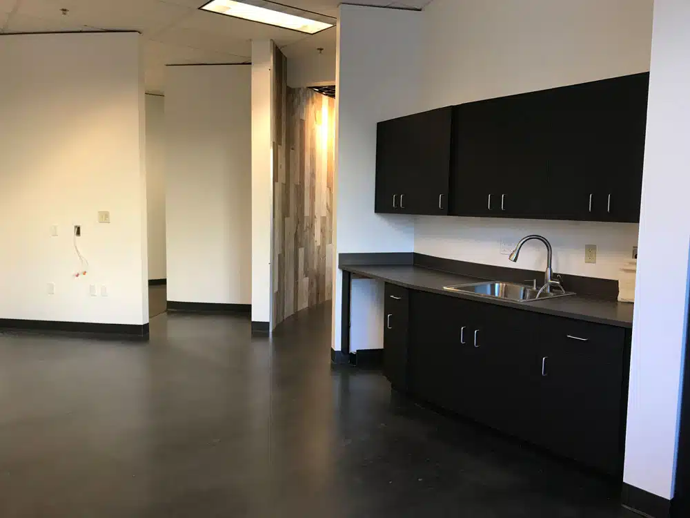 An empty kitchen with black cabinets and a sink