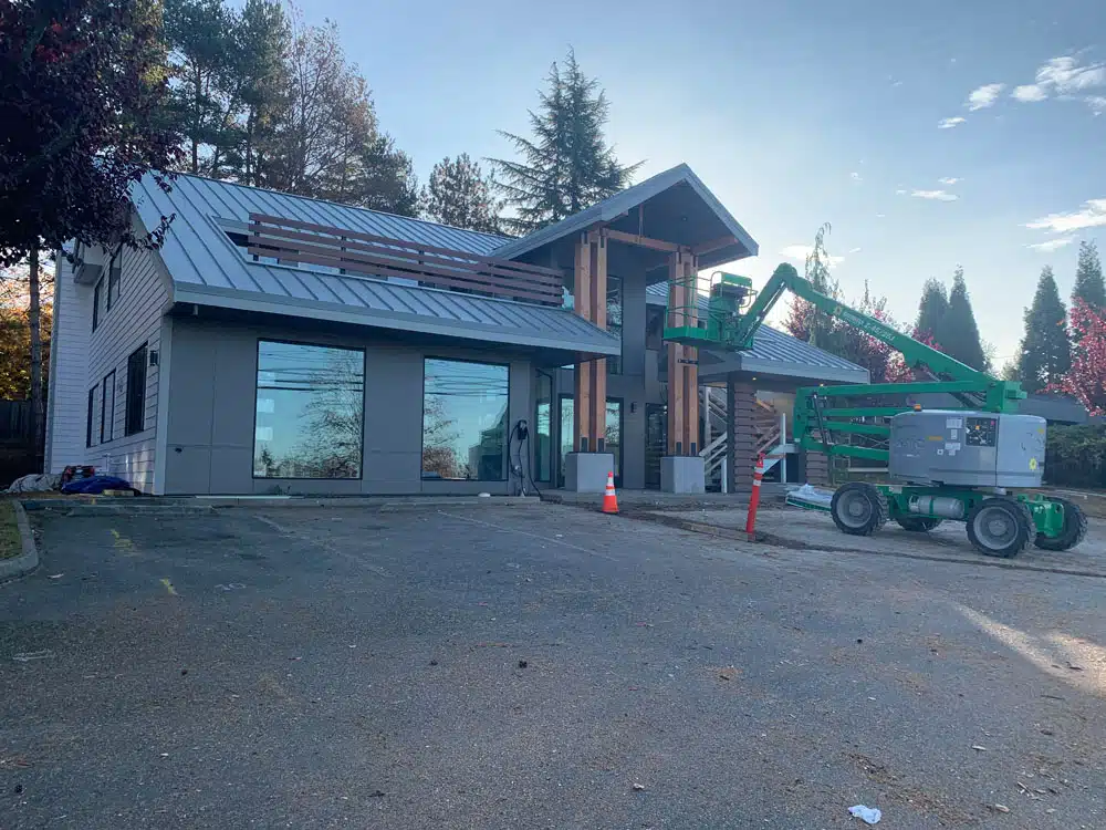 A large building under construction with a green crane parked in front of it.