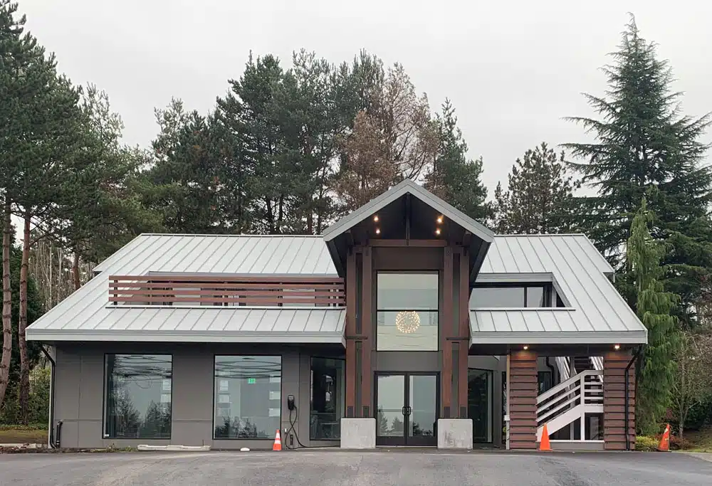 A large house with a metal roof is surrounded by trees