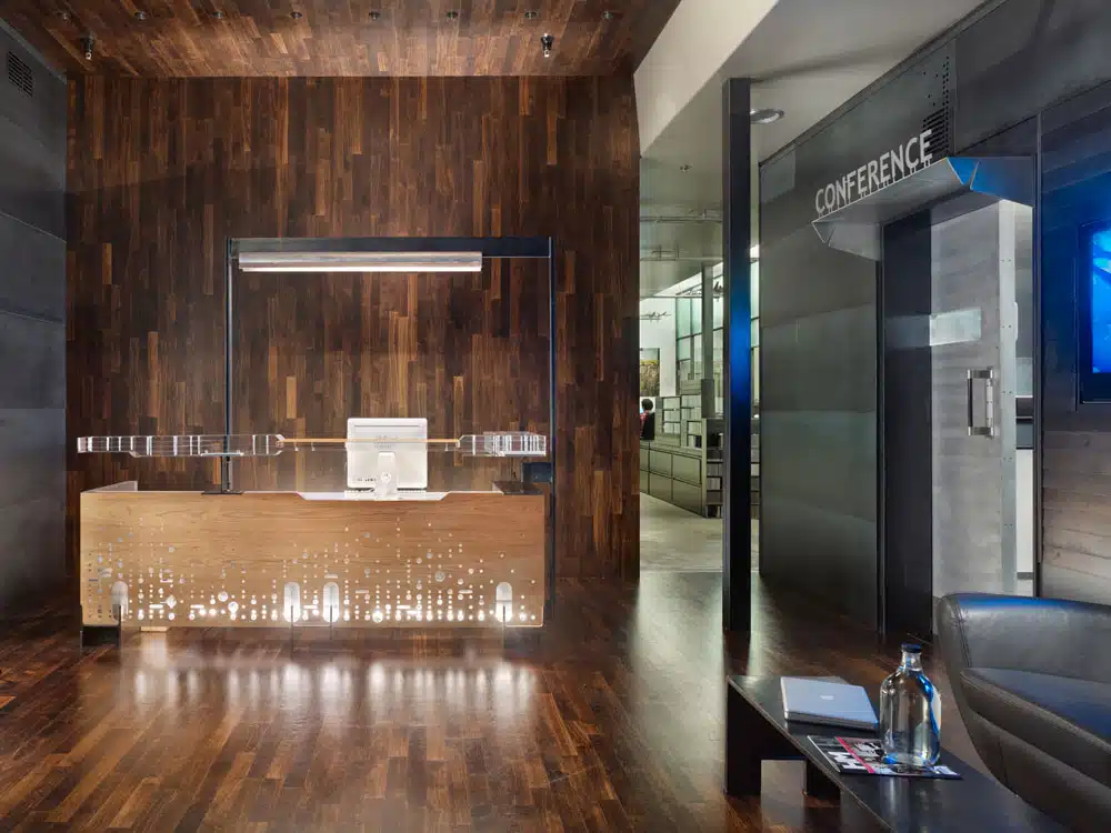 A reception area with a wooden desk and a conference room in the background.