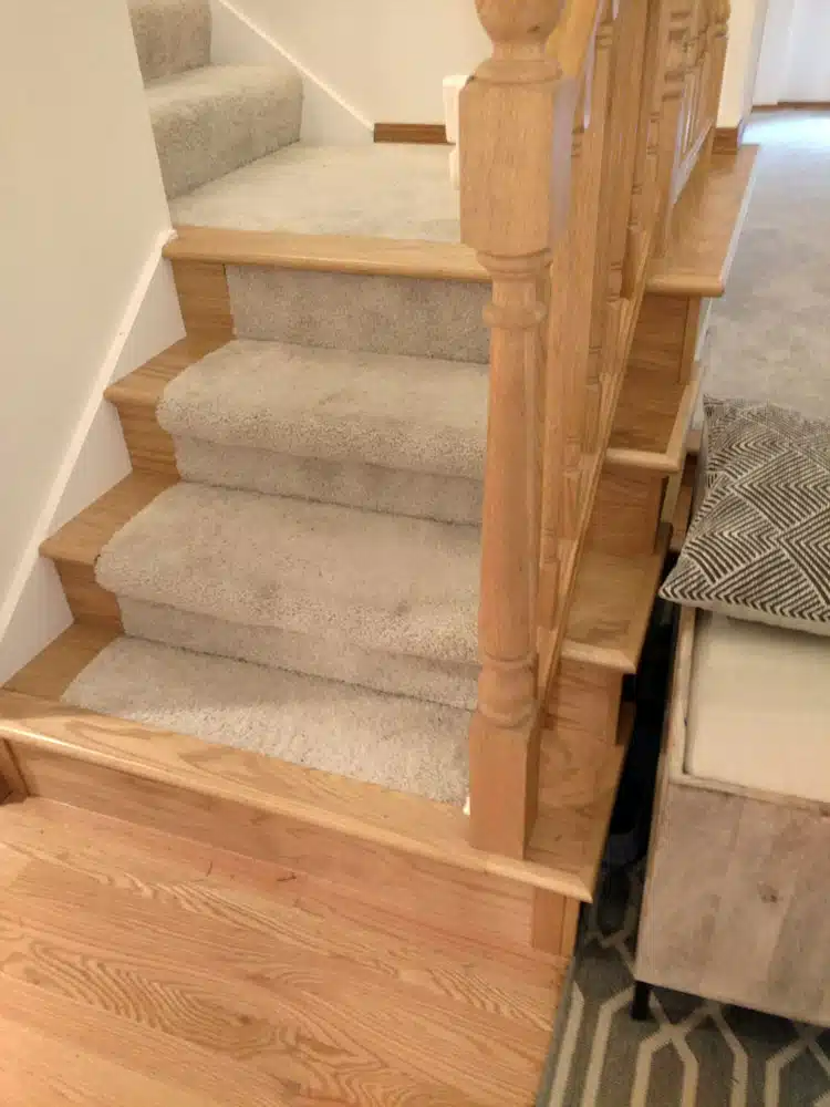 A wooden staircase with a carpeted staircase and a wooden railing.