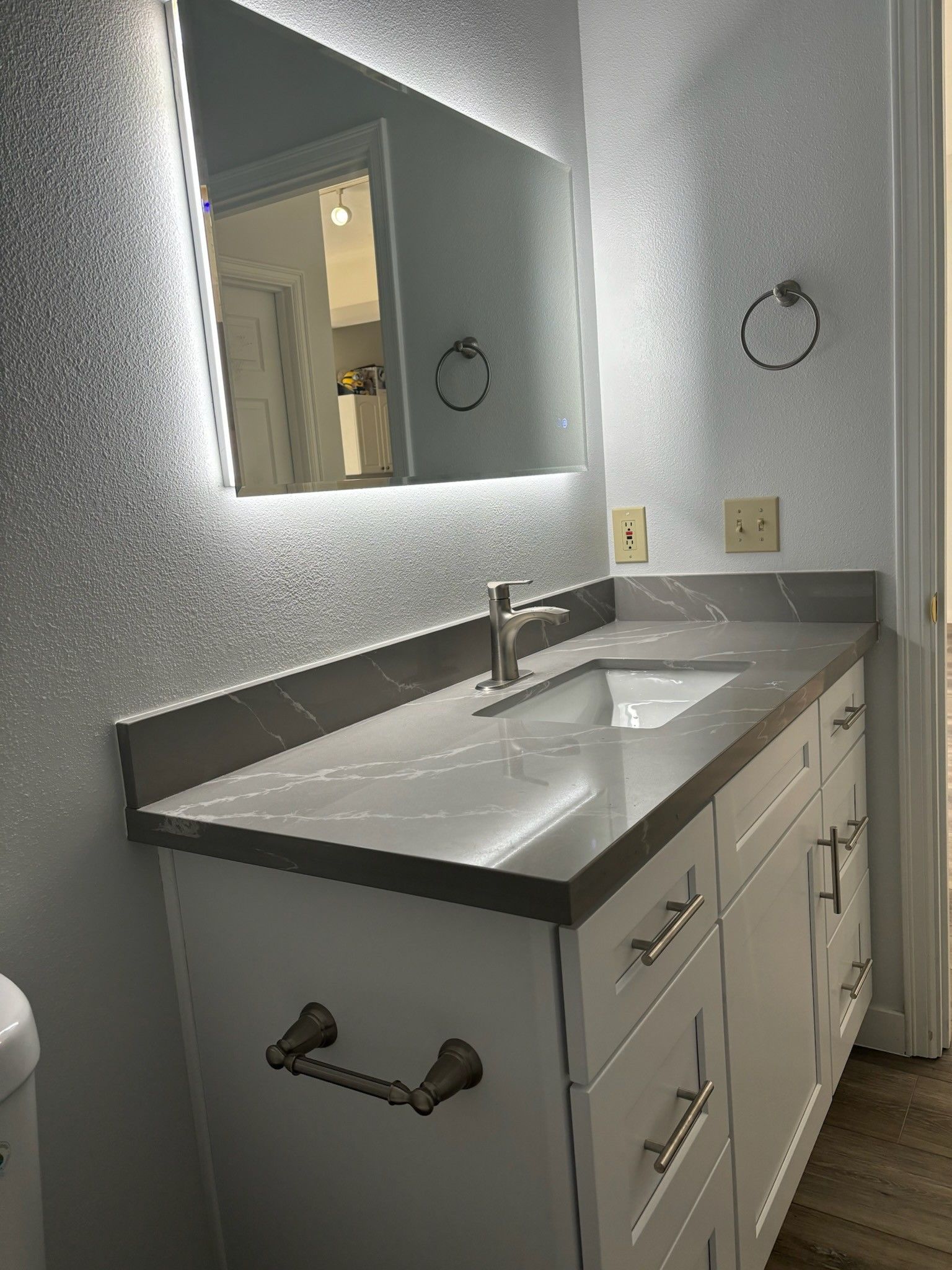 A bathroom with a sink , mirror and towel rack.