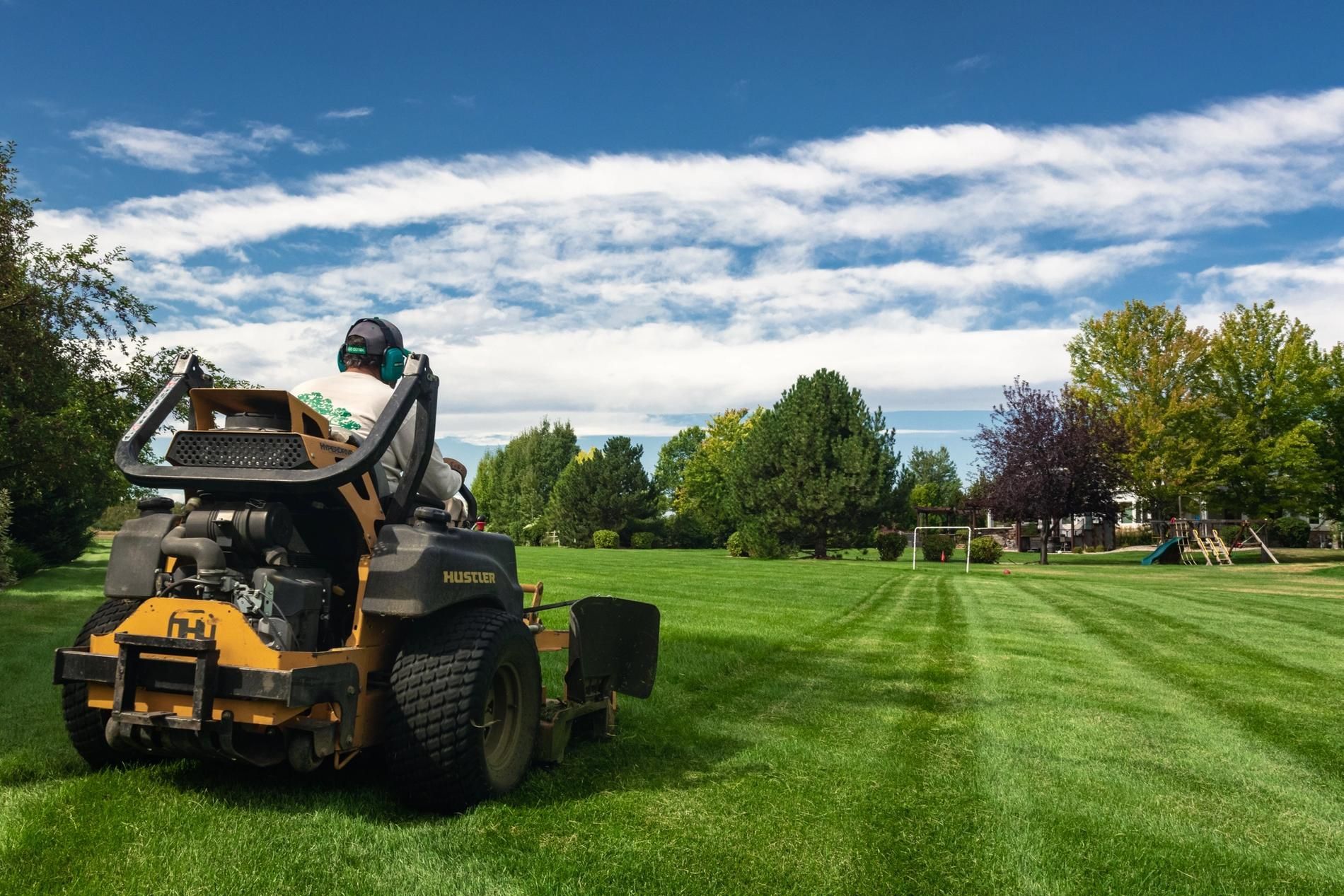 A man is riding a lawn mower on a lush green field.