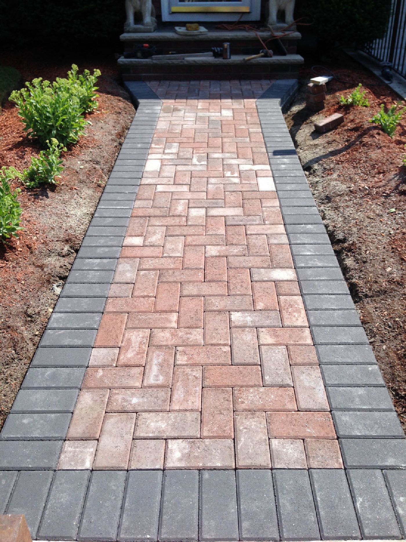 A brick walkway is being built in a garden