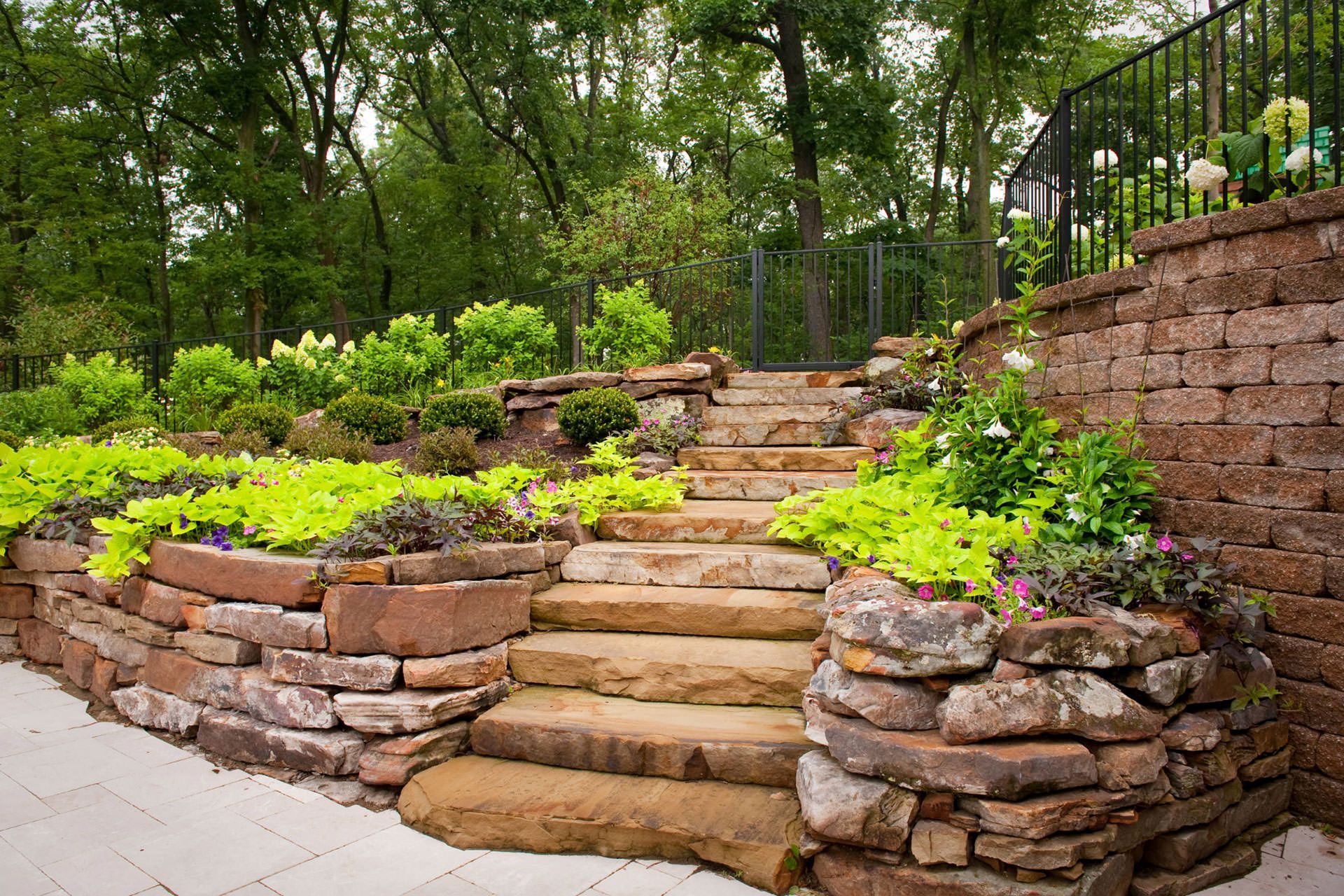 A stone wall with stairs leading up to it in a garden