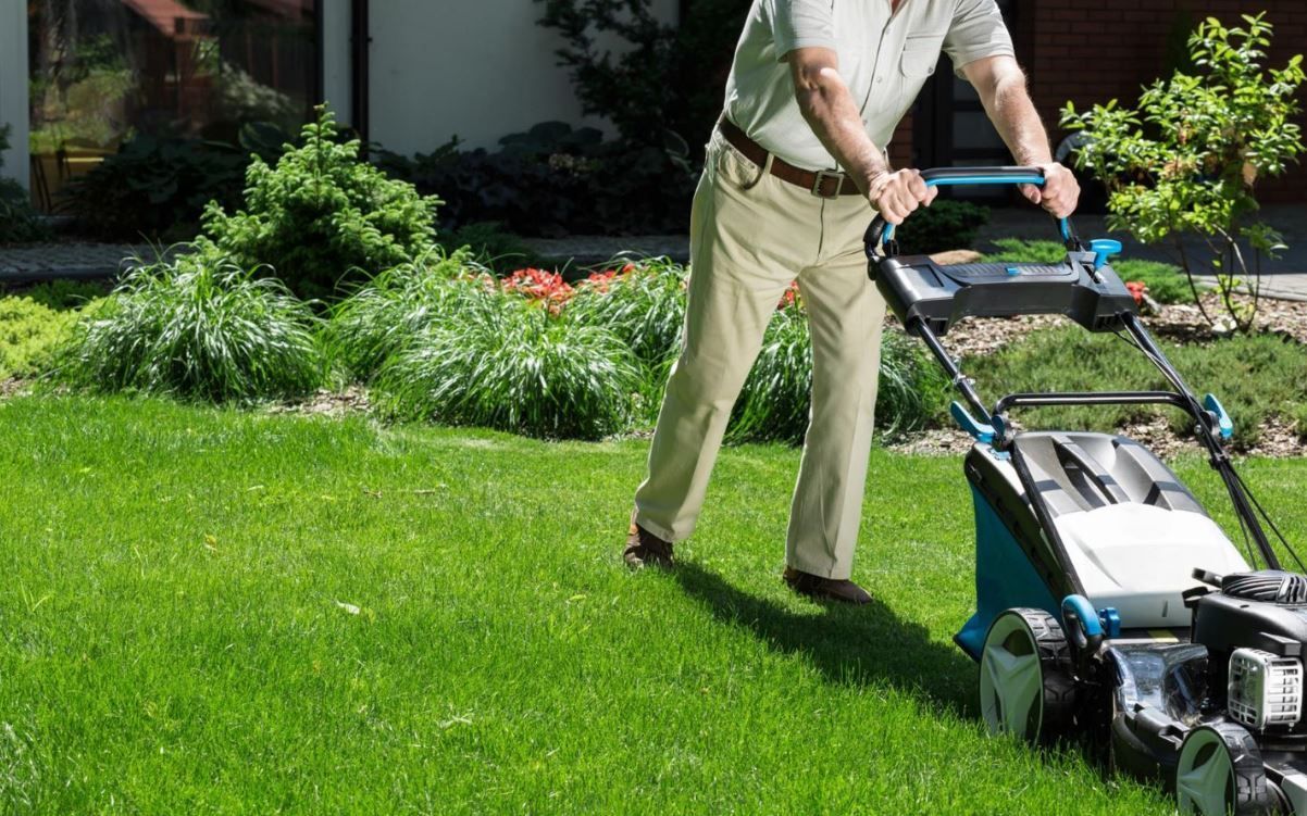 A man is mowing his lawn with a lawn mower.