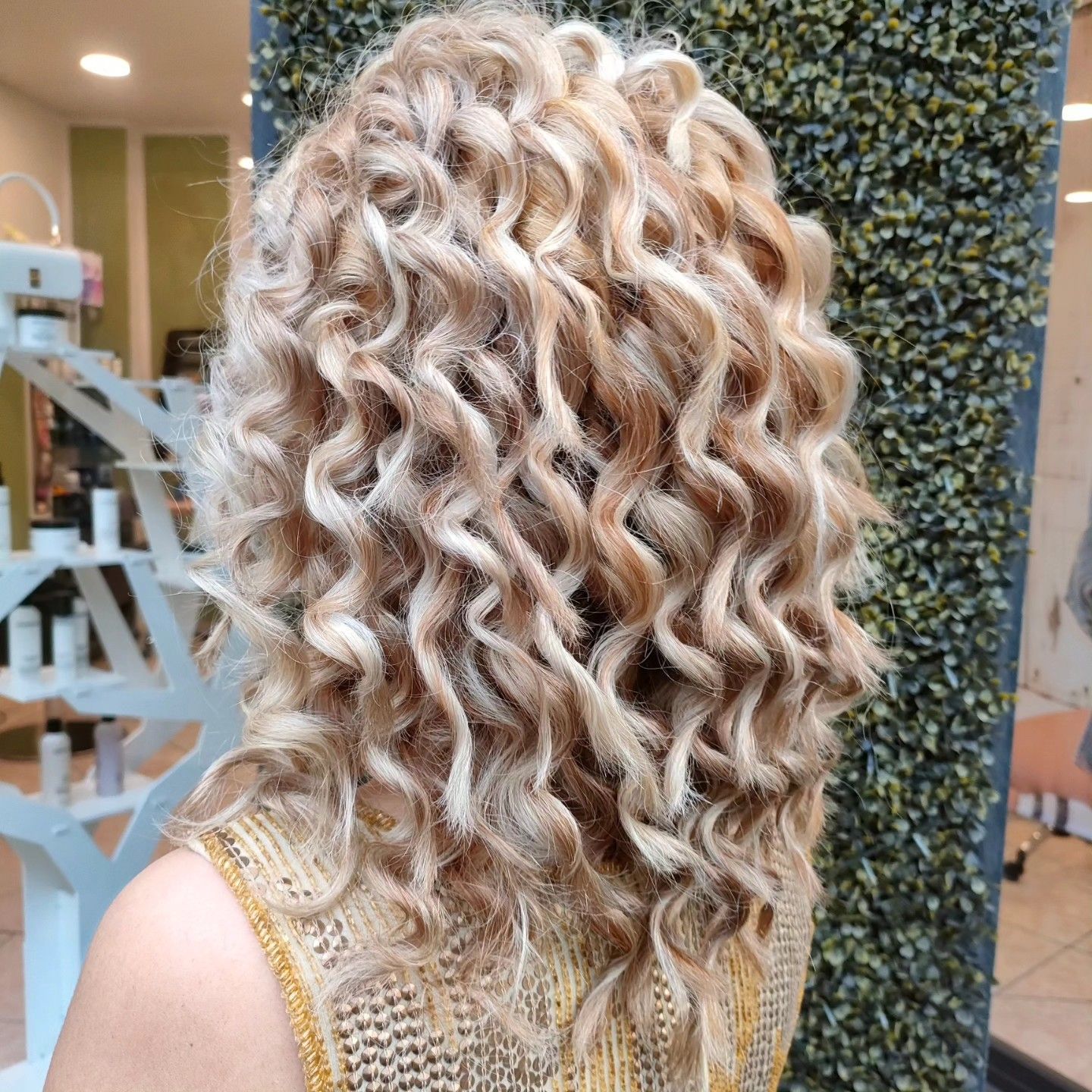 Vista da dietro di capelli biondi e ricci di media lunghezza in un salone di bellezza.