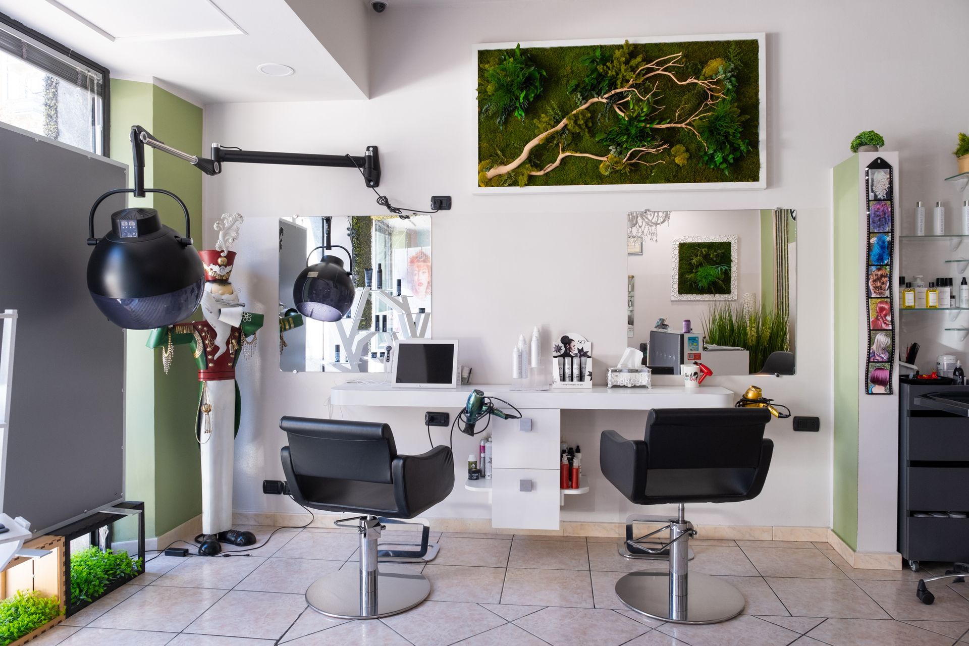 Una postazione di lavoro in un salone, composta da due sedie nere di fronte a degli specchi, una scrivania bianca e una composizione a parete con piante stabilizzate.