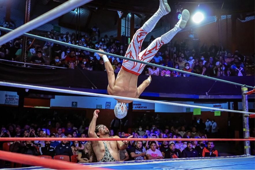 Un luchador está haciendo una parada de manos en un ring de lucha libre.
