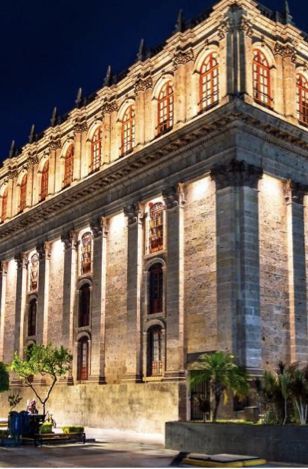 Un gran edificio con columnas se ilumina por la noche.