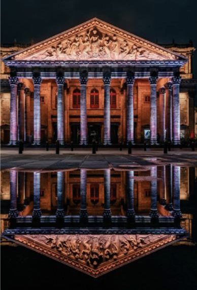 Un gran edificio con columnas se refleja en el agua.