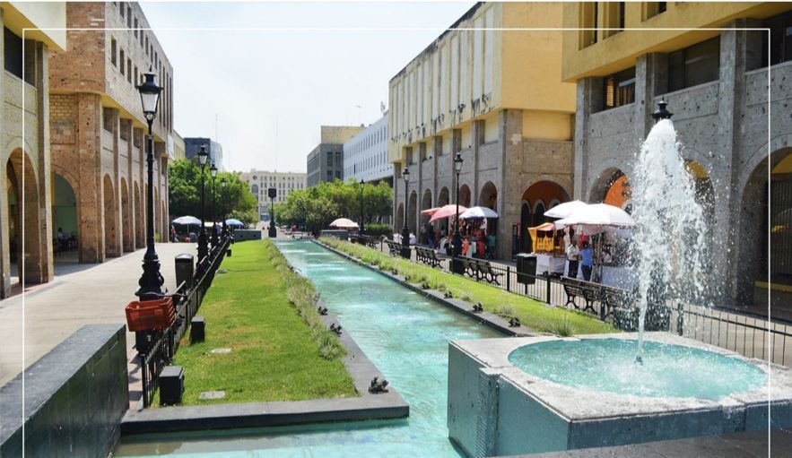 Una fuente en medio de una calle con edificios al fondo.