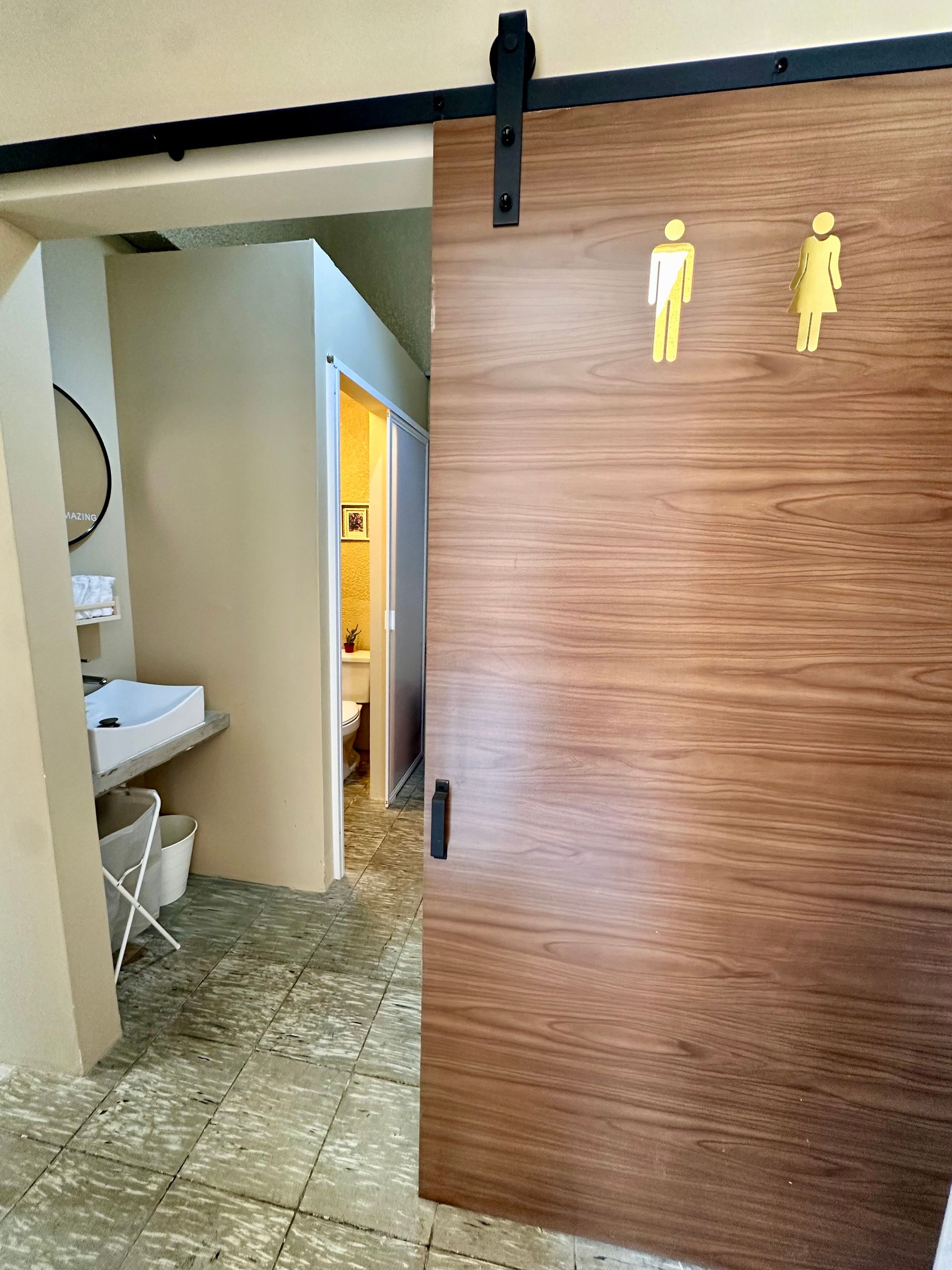 Un baño con una puerta corrediza tipo granero que conduce a un inodoro.