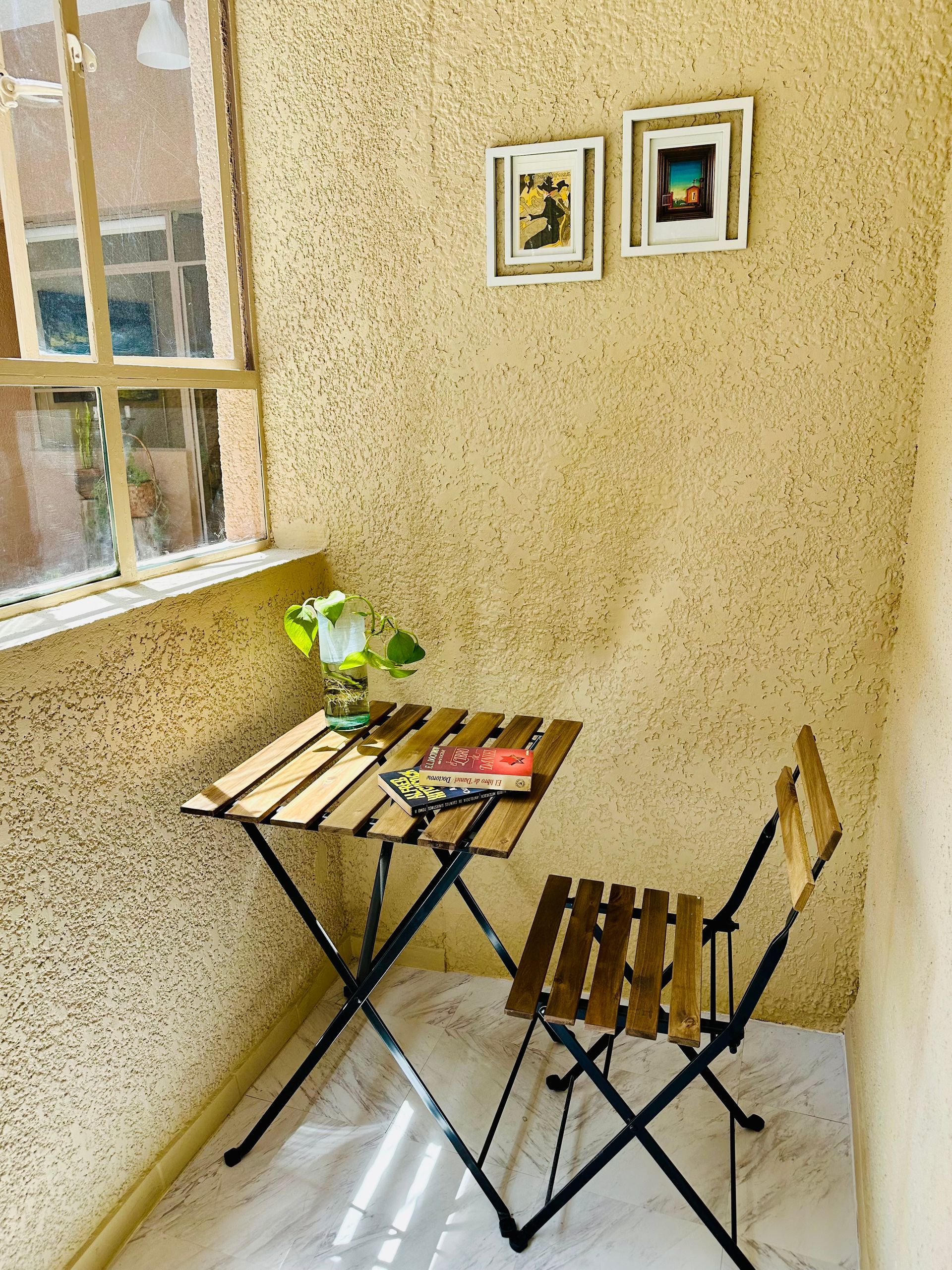 Una mesa pequeña y sillas en una habitación con ventana.