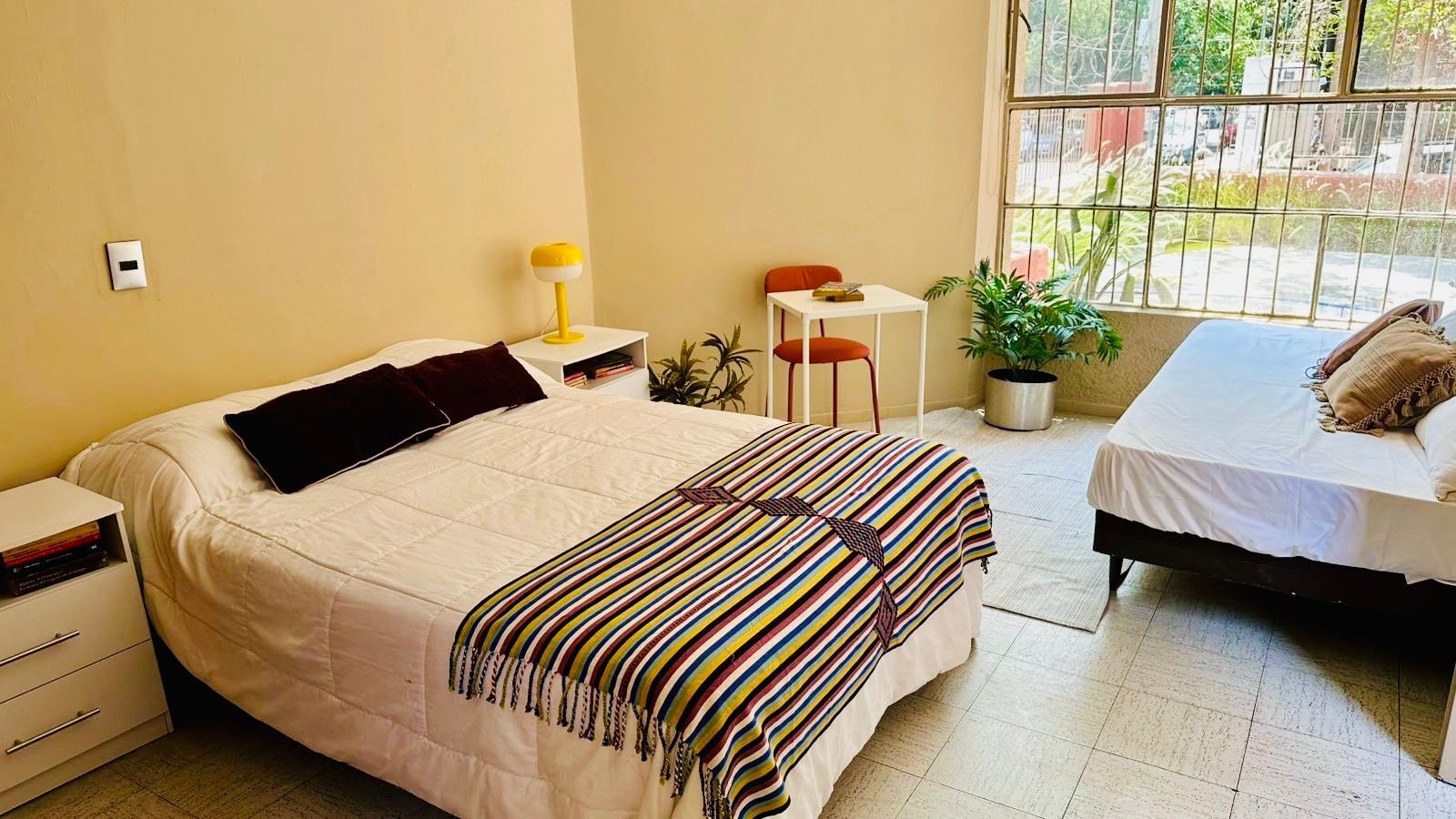 Un dormitorio con dos camas, una mesa y una ventana.