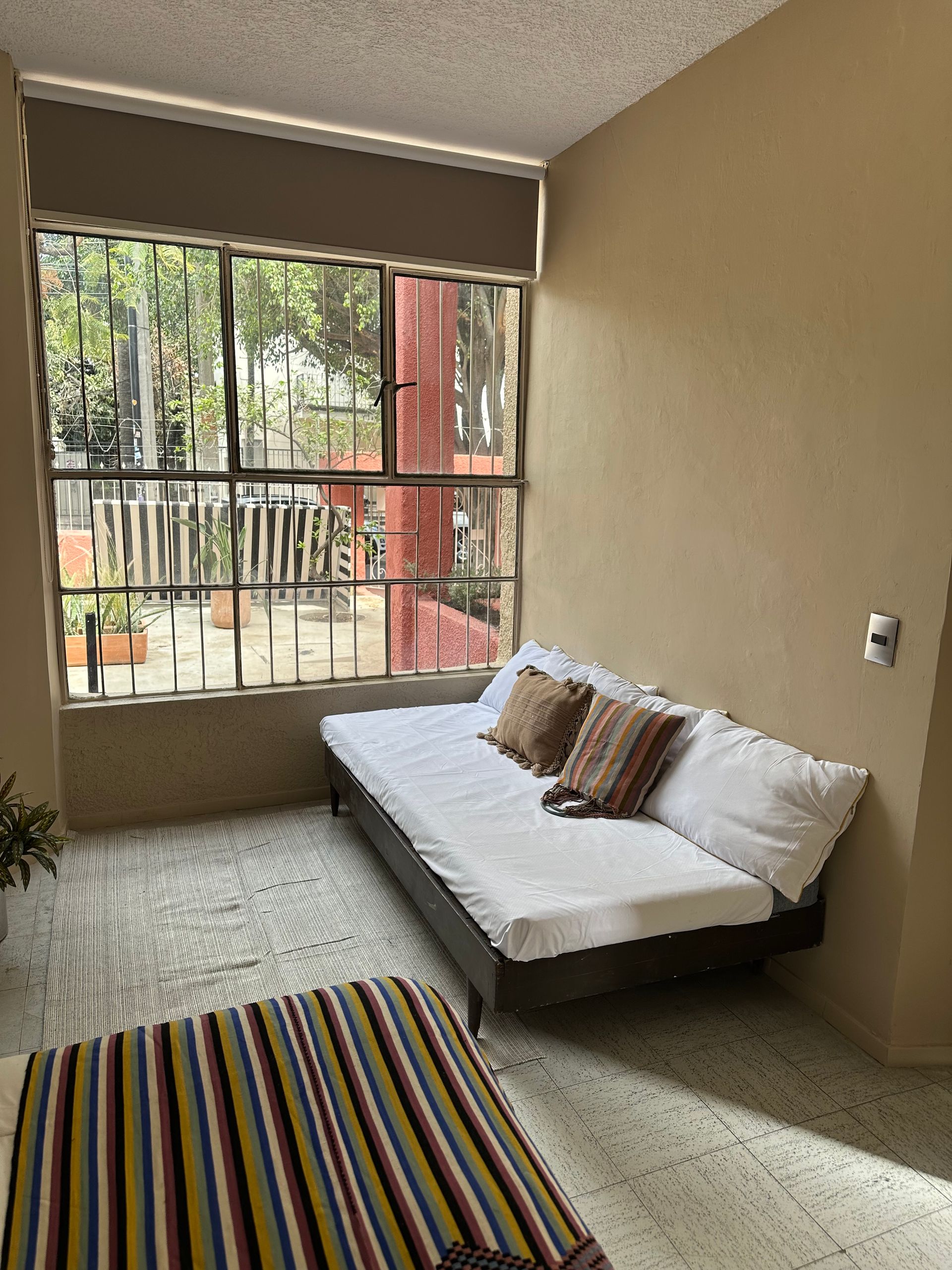 Una sala de estar con un sofá y una alfombra frente a una ventana.