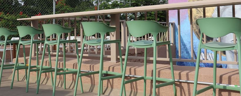Una fila de taburetes verdes junto a una larga mesa de madera.