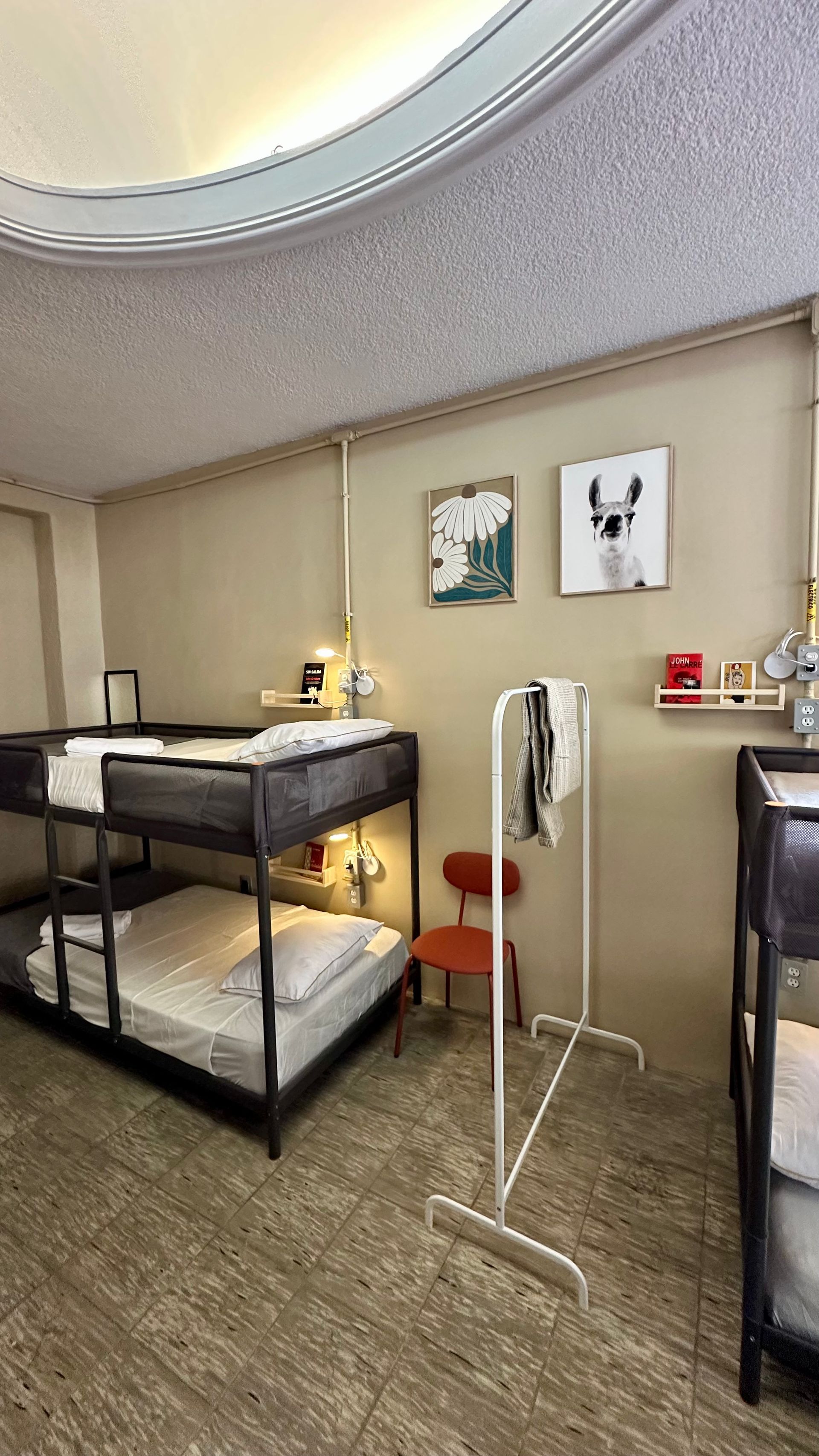 Un dormitorio con literas, una silla y un perchero.