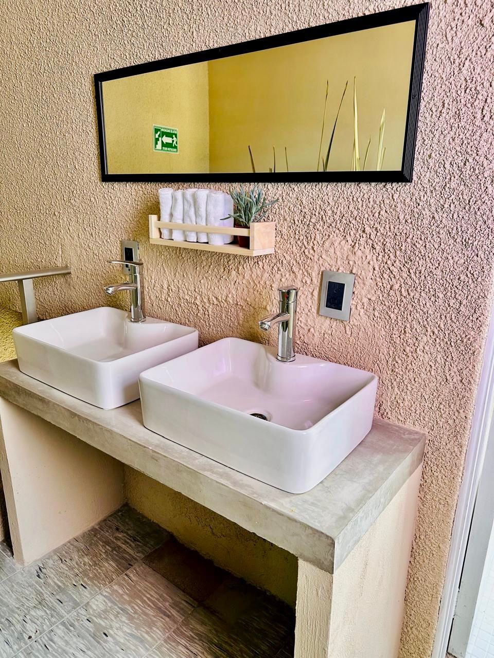 Un baño con dos lavabos y un espejo grande.