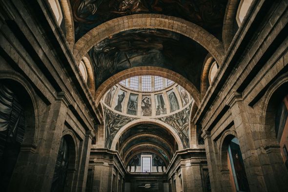 Mirando hacia el techo de una iglesia con arcos y una cúpula.