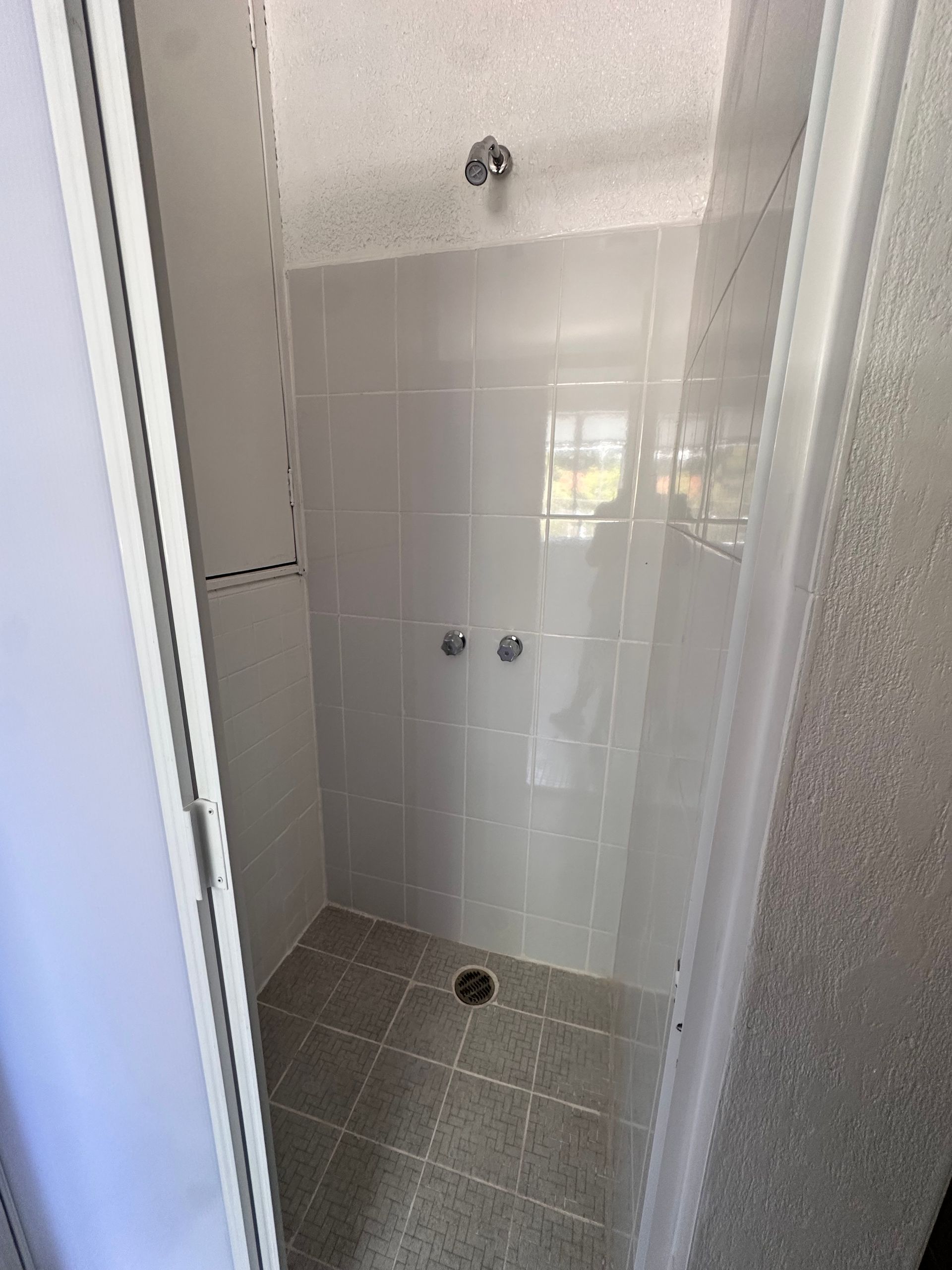 Un baño con ducha a ras de suelo y suelo de baldosas.