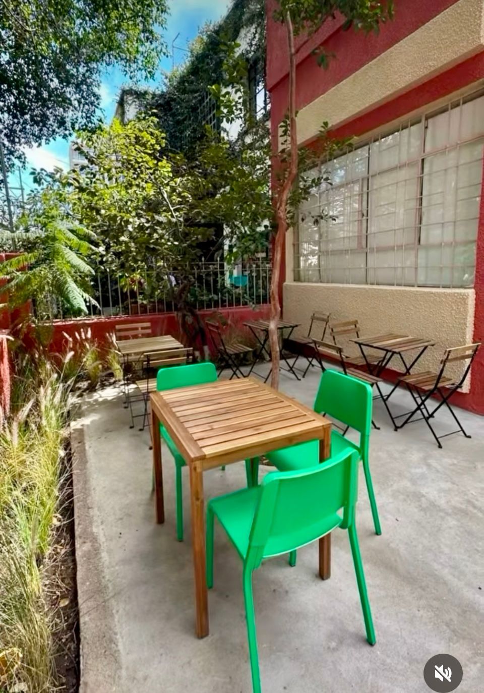 Un patio con sillas y mesas verdes frente a un edificio.