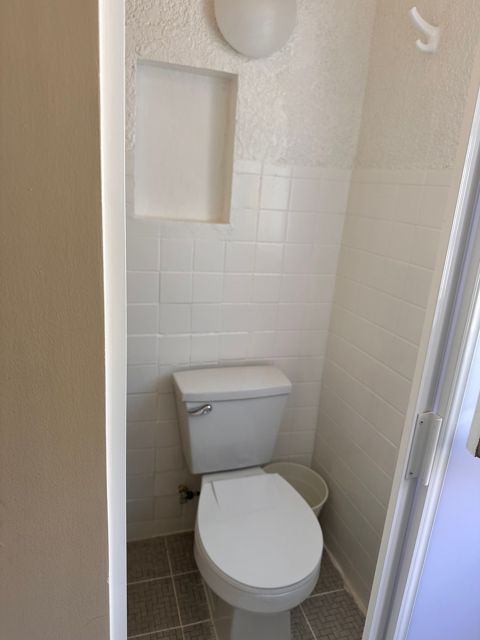 Hay un inodoro en un baño pequeño al lado de una puerta.