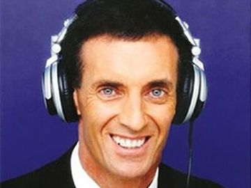 Man wearing large silver headphones and smiling against a purple background