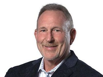 Portrait of a smiling man in a dark blazer and white shirt against a white background