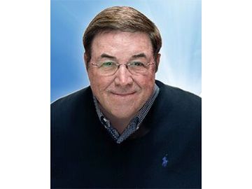 Portrait of a smiling man in glasses wearing a navy sweater against a blue background