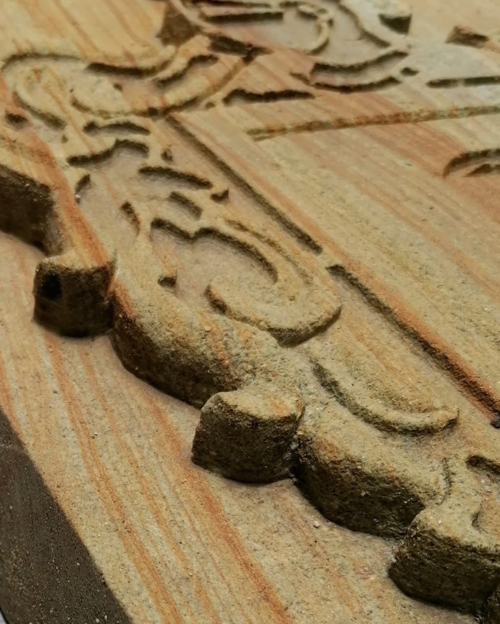 Primer plano de un patrón decorativo y ornamentado tallado en madera de color claro, que muestra profundidad y textura.