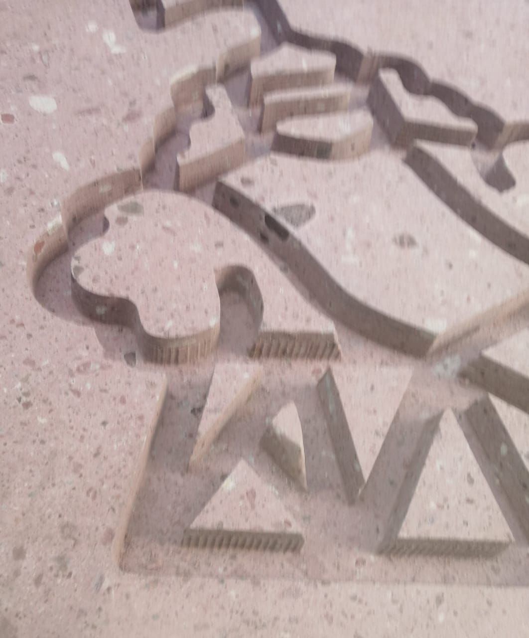 Primer plano de una superficie de piedra tallada con patrones y segmentos geométricos, que muestra un material texturizado de color marrón claro.