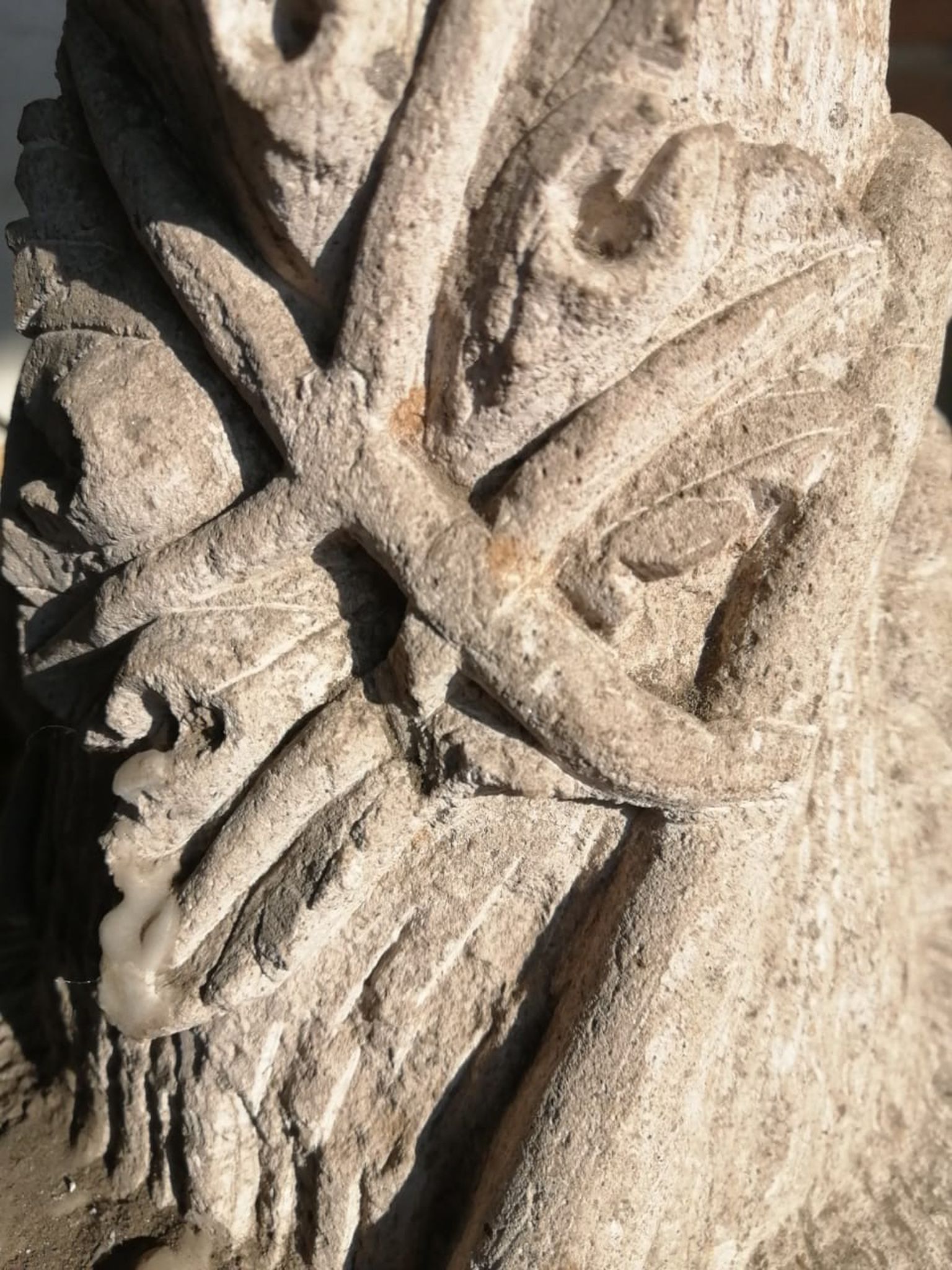 Primer plano de un relieve tallado en piedra erosionada que presenta líneas geométricas y formas circulares huecas sobre una superficie rugosa.