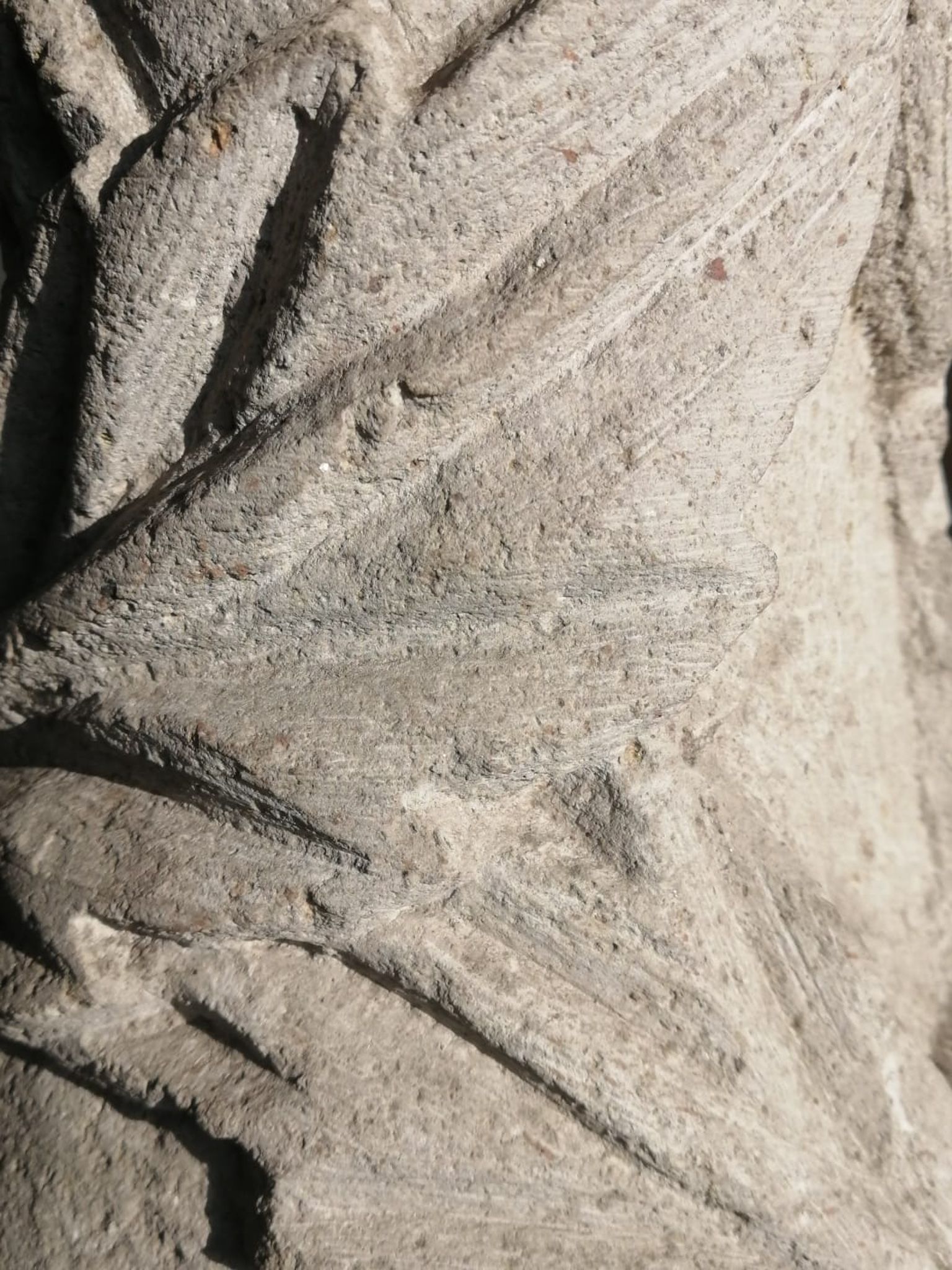 Primer plano de una superficie de piedra gris y rugosa con surcos diagonales tallados que crean un patrón geométrico texturizado.