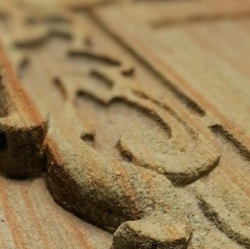 Primer plano de una superficie de madera tallada con un elaborado relieve ondulado en tonos marrón claro y tostado.