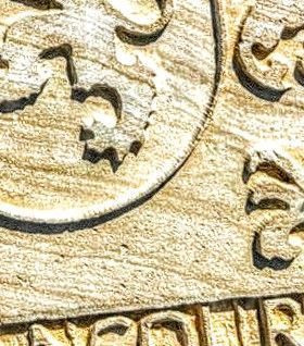 Primer plano de un relieve de piedra tallada con motivos de leones heráldicos y letras talladas parcialmente en la parte inferior.