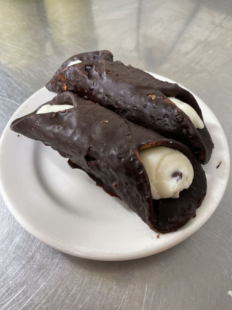 Two chocolate cannoli on a white plate on a table.